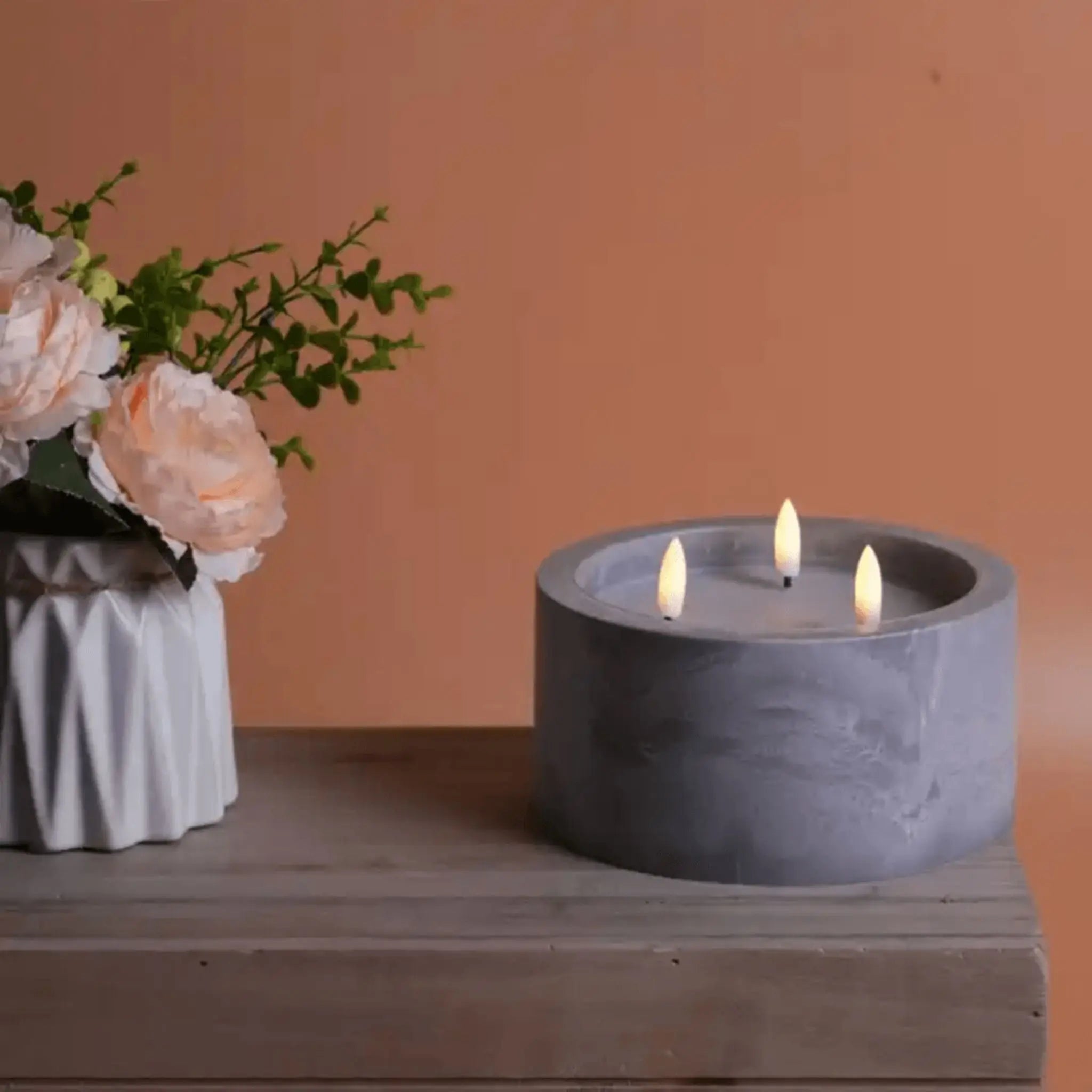 Bougie effet marbre avec flammes LED, accompagnée d'un vase de fleurs, pour décoration intérieure élégante.