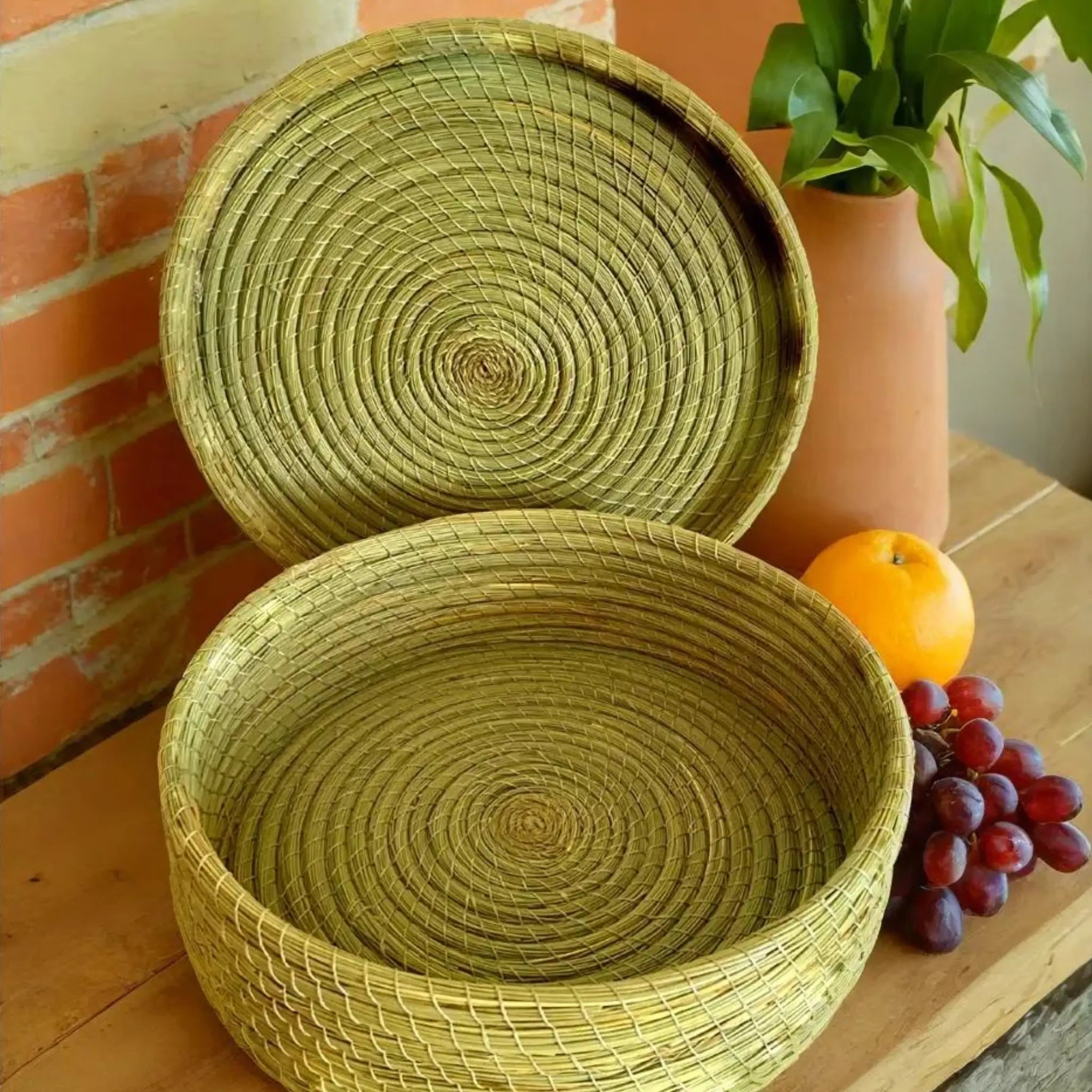 Grande boîte ronde en halfa avec couvercle, panier artisanal exposé sur une table en bois avec fruits frais.