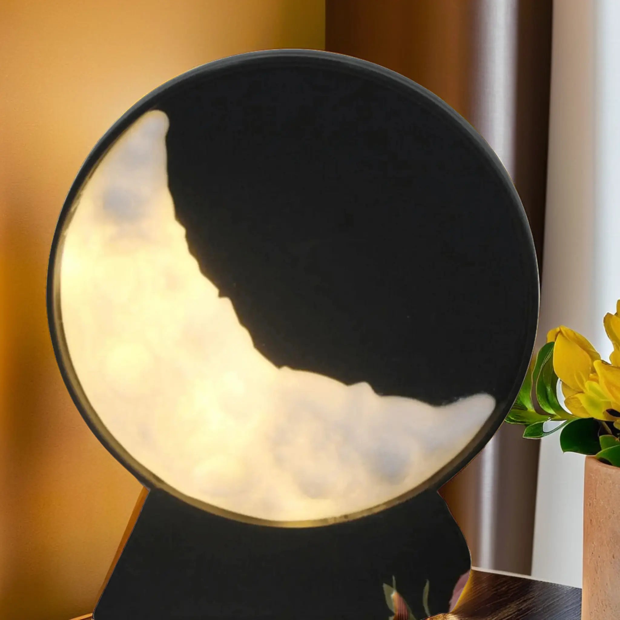Lampe en croissant de lune avec une lumière dorée sur une table, accompagnée de fleurs jaunes éclatantes et un arrière-plan chaleureux.
