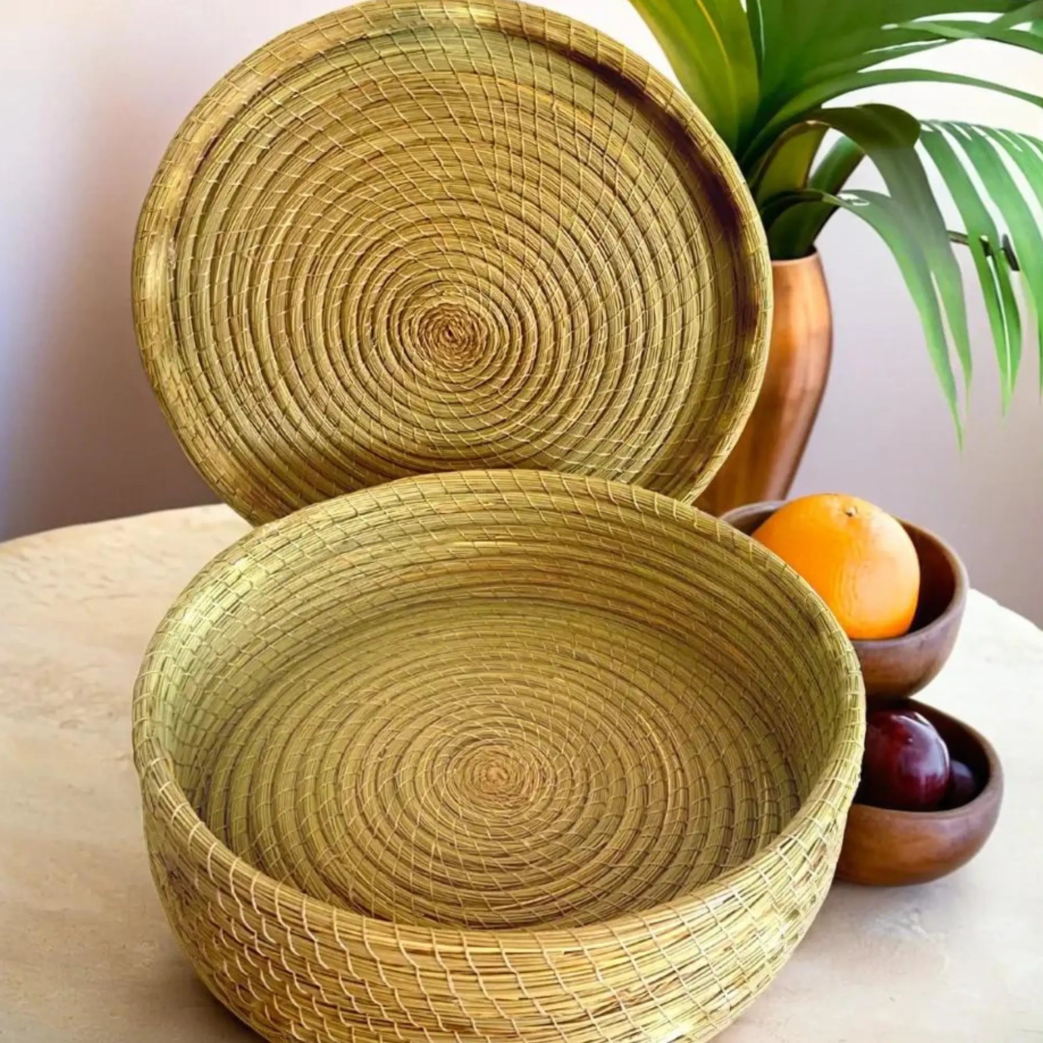 Panier rond en halfa avec couvercle, exposé avec des fruits sur une table en bois.