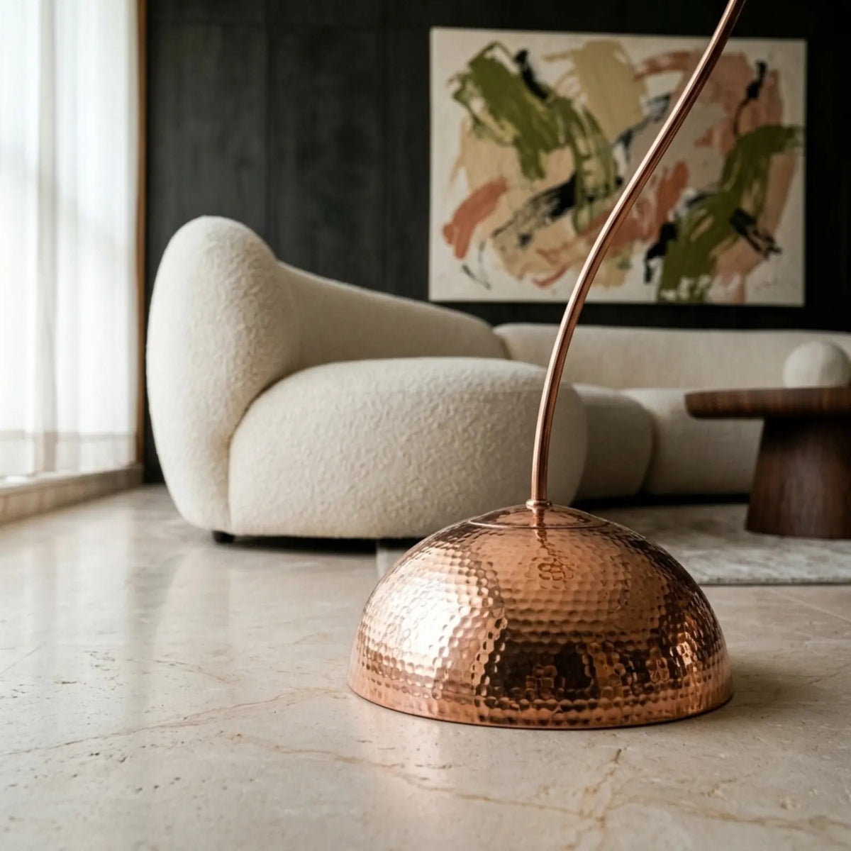 Base demi-sphère en cuivre rosé martelé du lampadaire, canapé bouclette en arrière-plan