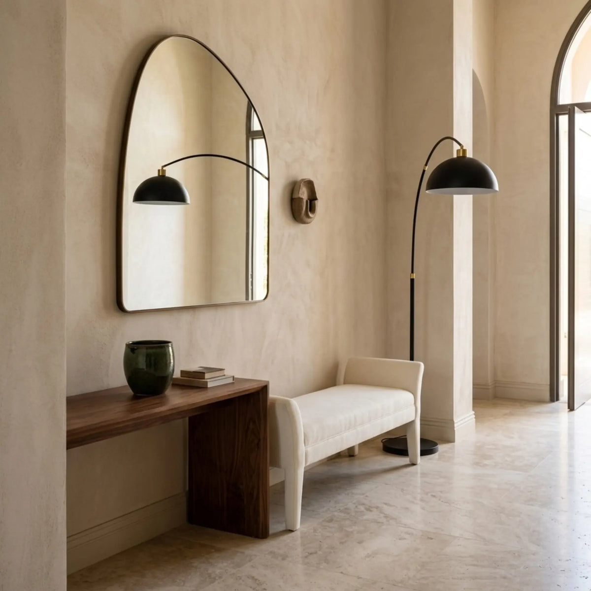 Lampadaire arc noir et doré dans une entrée, à côté d'un banc blanc, d'une console en noyer et d'un grand miroir