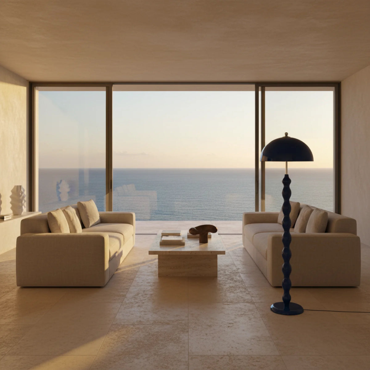 Lampadaire bleu près d'un canapé beige dans un salon face à la mer au coucher du soleil