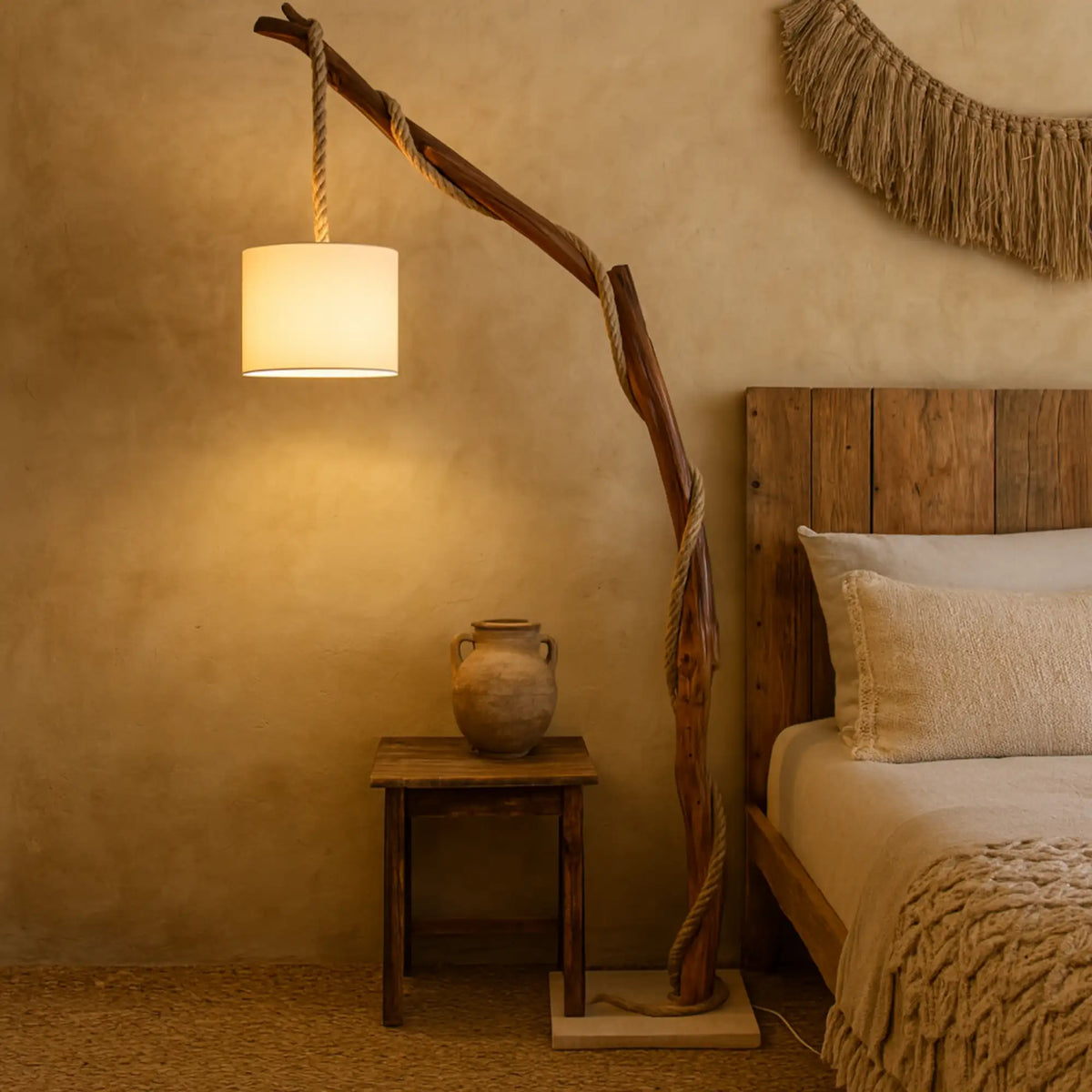 Lampadaire chambre en bois naturel allumé au-dessus d'une table de chevet, à côté d'une tête de lit en bois