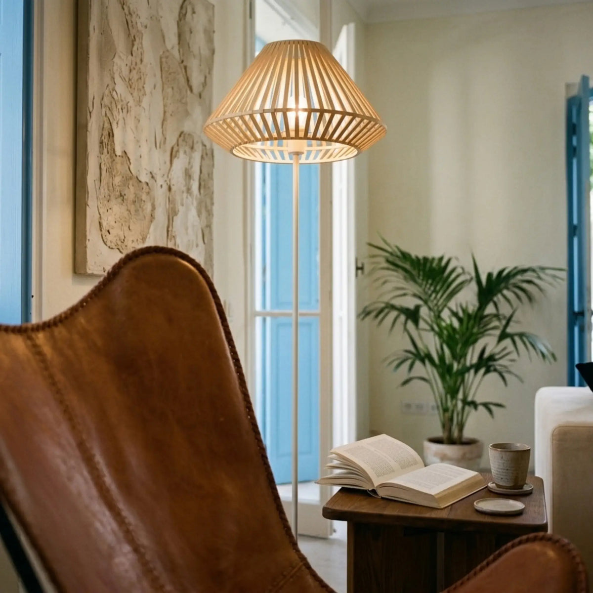 Lampadaire allumé au-dessus d'un fauteuil papillon en cuir, près d'une table d'appoint avec un livre ouvert