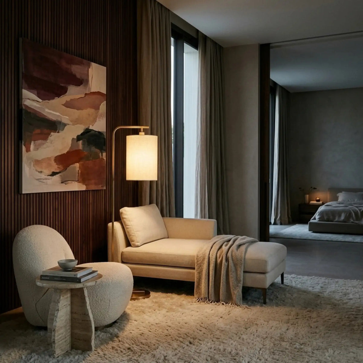 Lampadaire doré allumé derrière une méridienne beige, avec fauteuil bouclé et chambre en arrière-plan