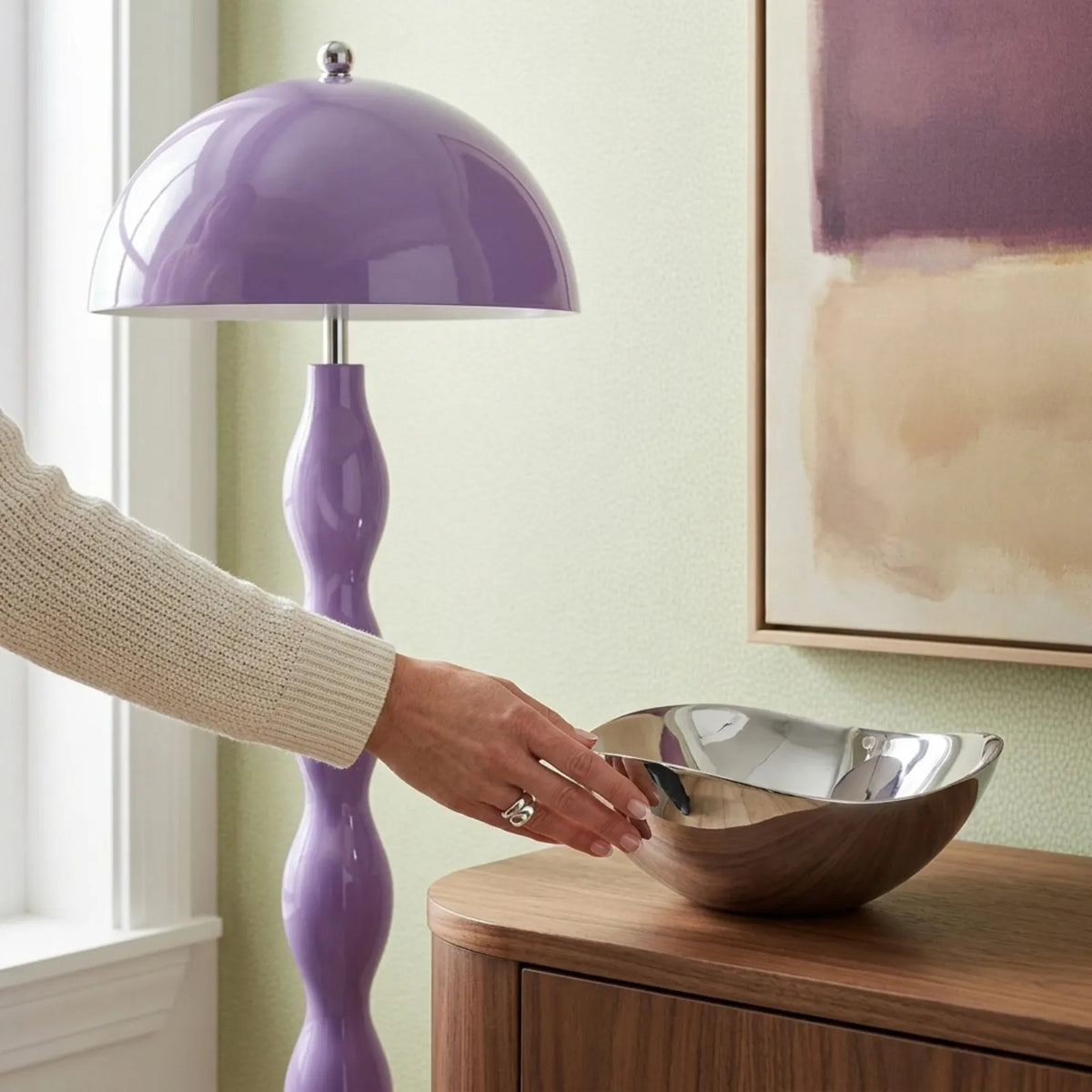 Lampadaire lilas à côté d'un buffet en noyer et d'une coupe en métal poli, près d'une fenêtre