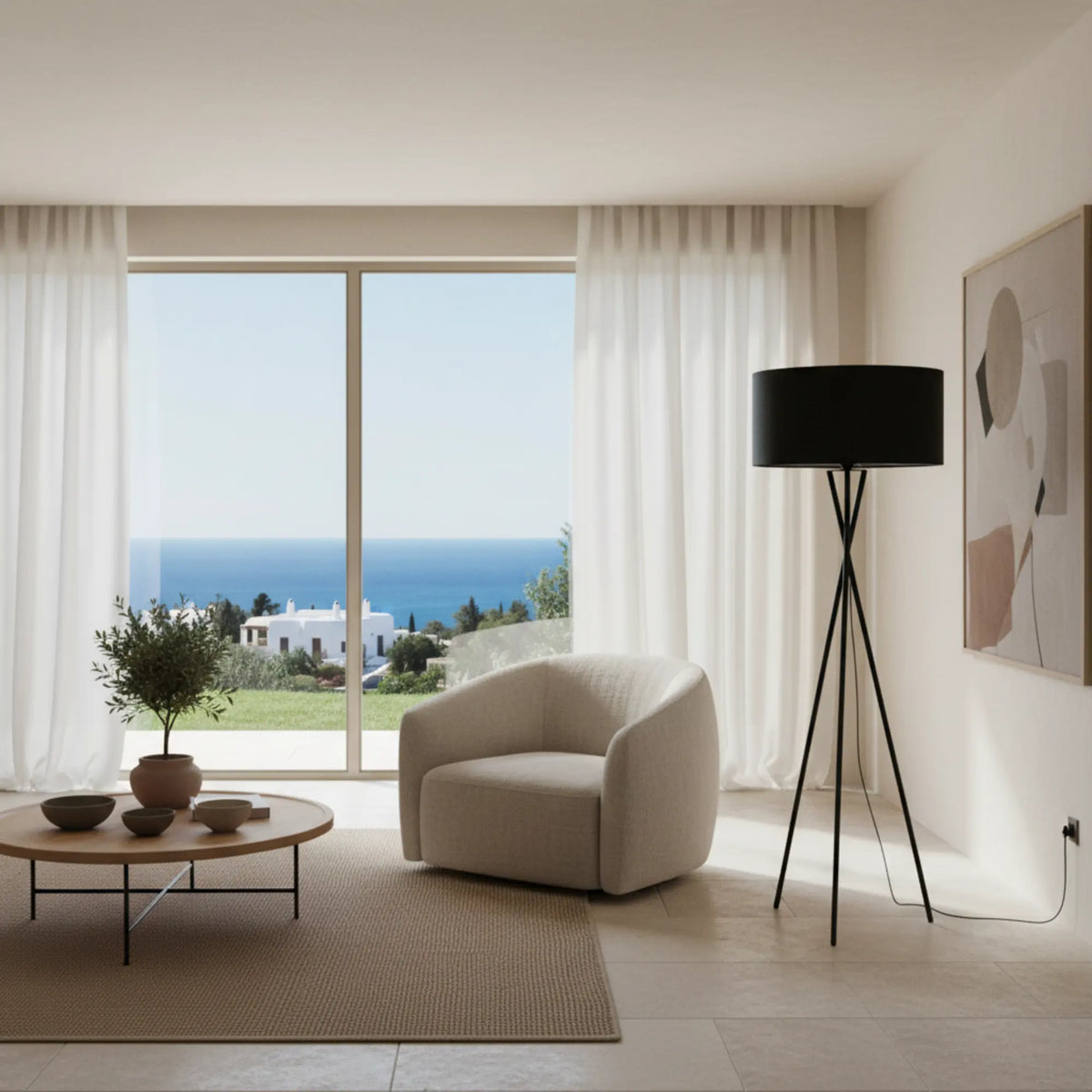 Lampadaire noir à abat-jour tissu dans un salon clair avec fauteuil arrondi blanc et baie vitrée sur la mer