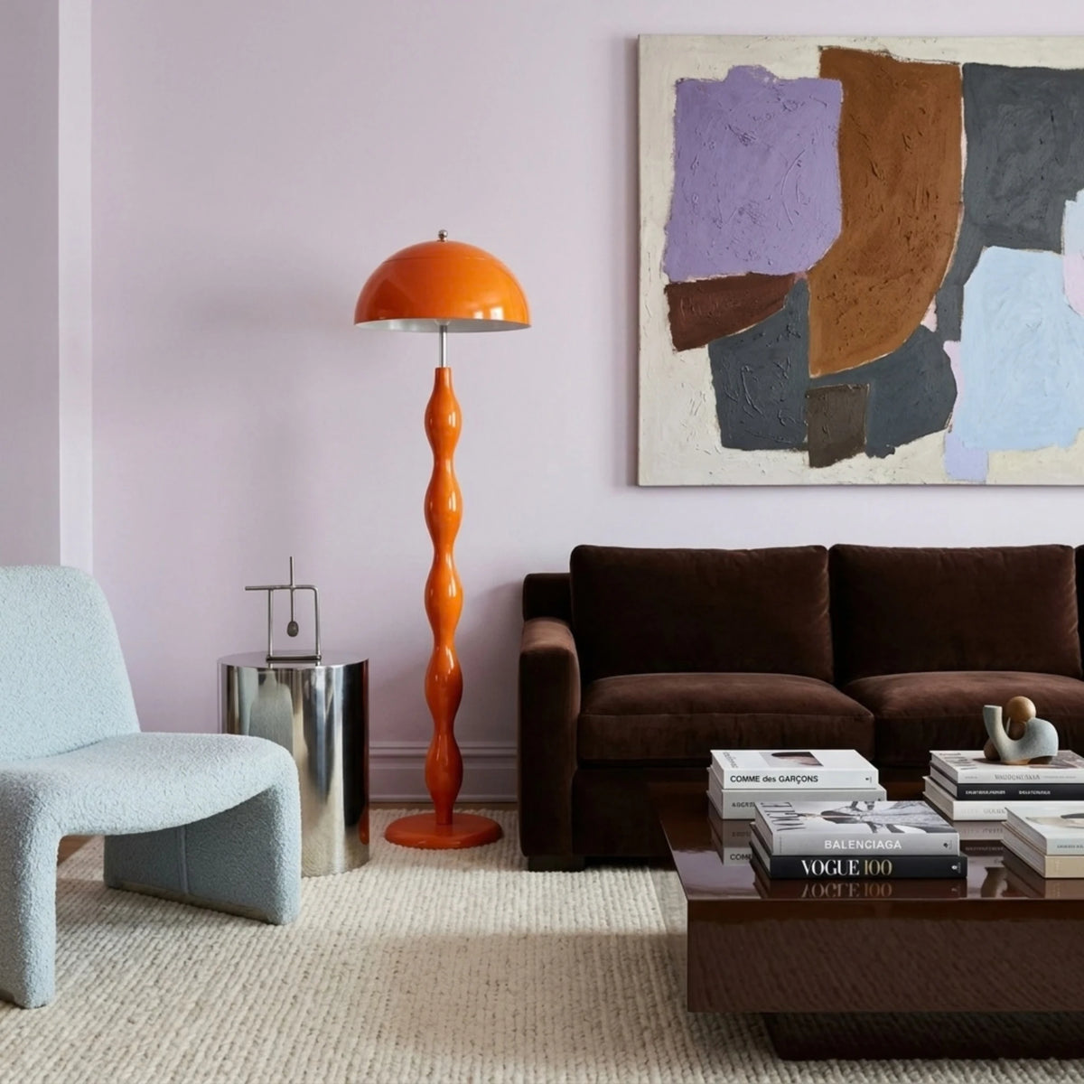 Lampadaire de salon orange devant un mur lilas, entre un canapé chocolat et un fauteuil bleu clair