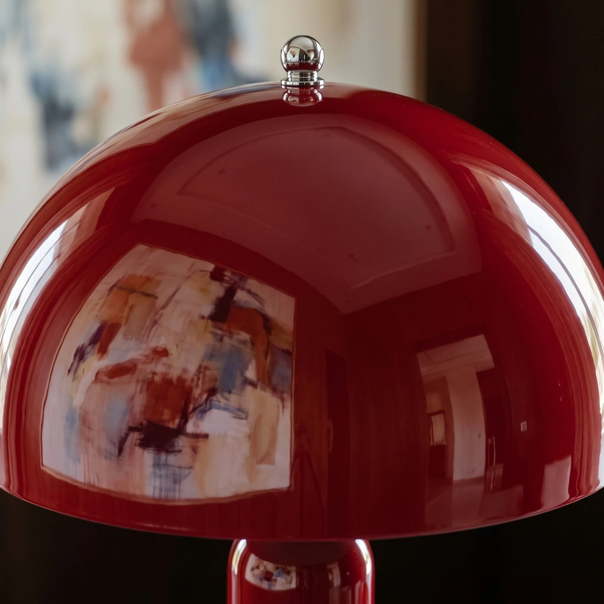 Détail du dôme rouge carmin laqué du lampadaire champignon, reflétant un tableau abstrait