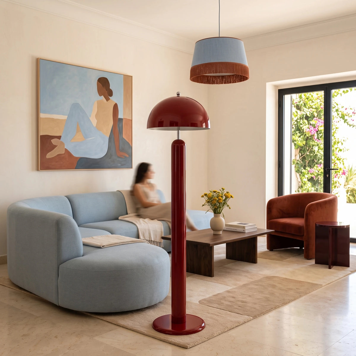 Lampadaire champignon rouge près d'un canapé courbe bleu clair et d'un fauteuil rouille, baie vitrée sur jardin
