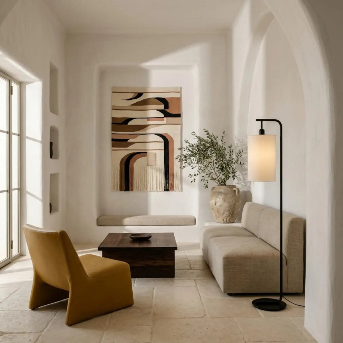 Lampadaire noir au bout d'un canapé beige dans un salon blanc aux arches méditerranéennes