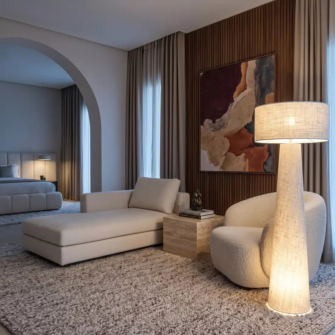 Lampadaire en lin allumé près d'un fauteuil blanc arrondi et d'une méridienne, dans un salon beige