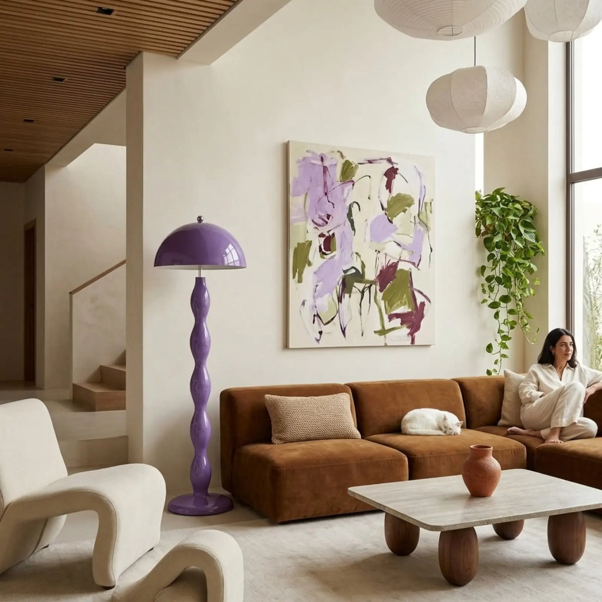 Lampadaire lilas dans un grand salon lumineux, près d'un canapé en velours cognac et d'un tableau abstrait