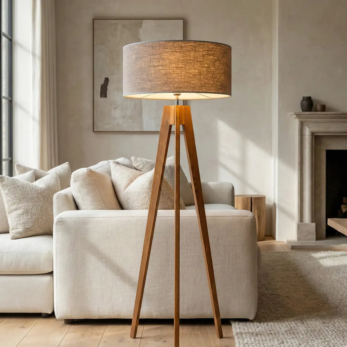 Lampadaire scandinave trépied allumé devant un canapé blanc, dans un salon avec cheminée