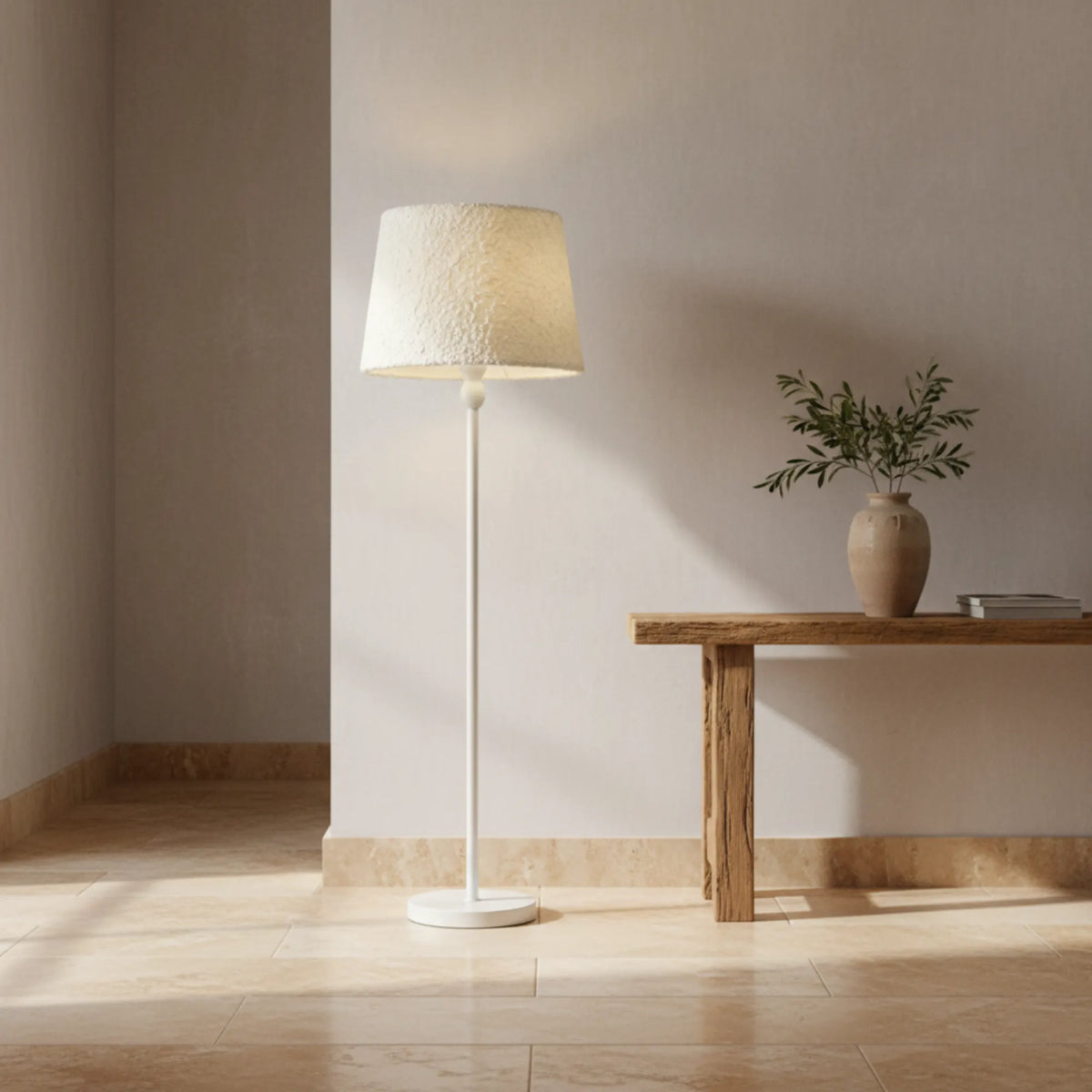 Lampadaire blanc à côté d'une console en bois avec vase et branchage, dans une entrée aux murs clairs