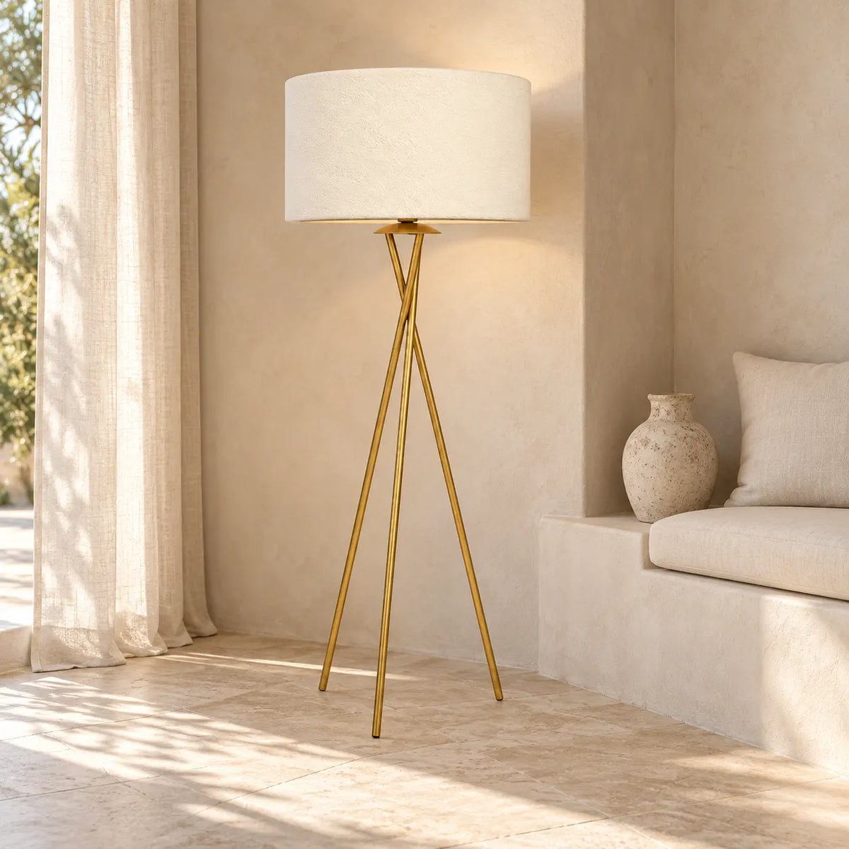Lampadaire trépied doré à côté d'une banquette maçonnée blanche et d'une jarre en céramique, sous la lumière du soleil