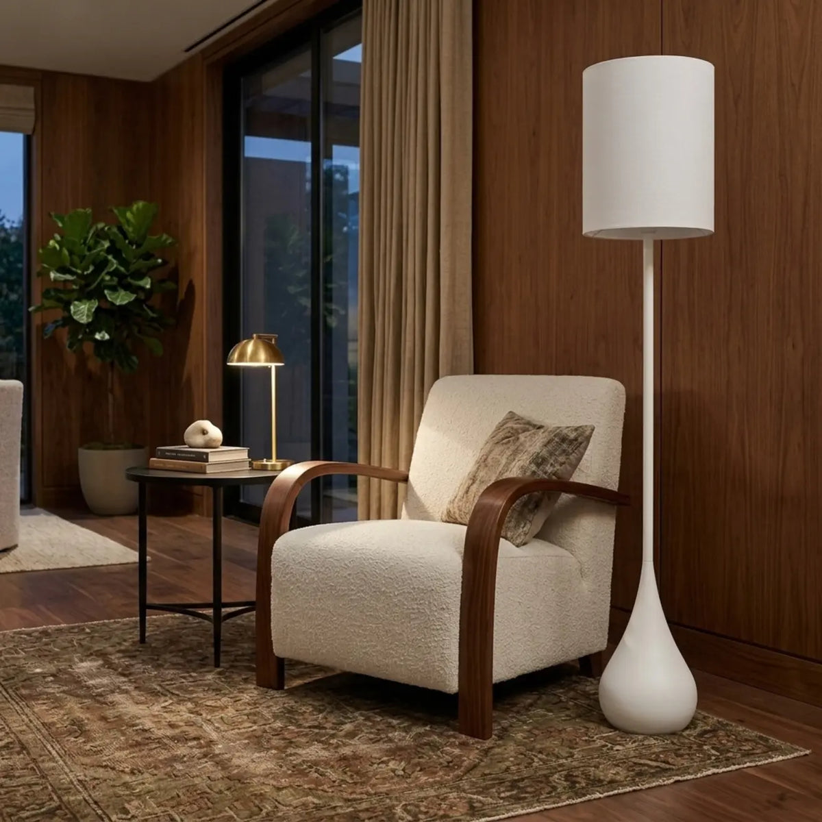 Lampadaire blanc Goutte à côté d'un fauteuil crème aux accoudoirs en bois, devant un mur en bois et une plante verte