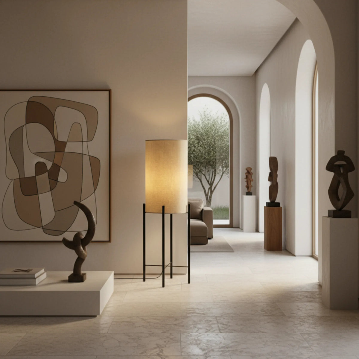 Lampe sur pied en lin allumée dans une entrée à arcades, entre un tableau abstrait et des sculptures