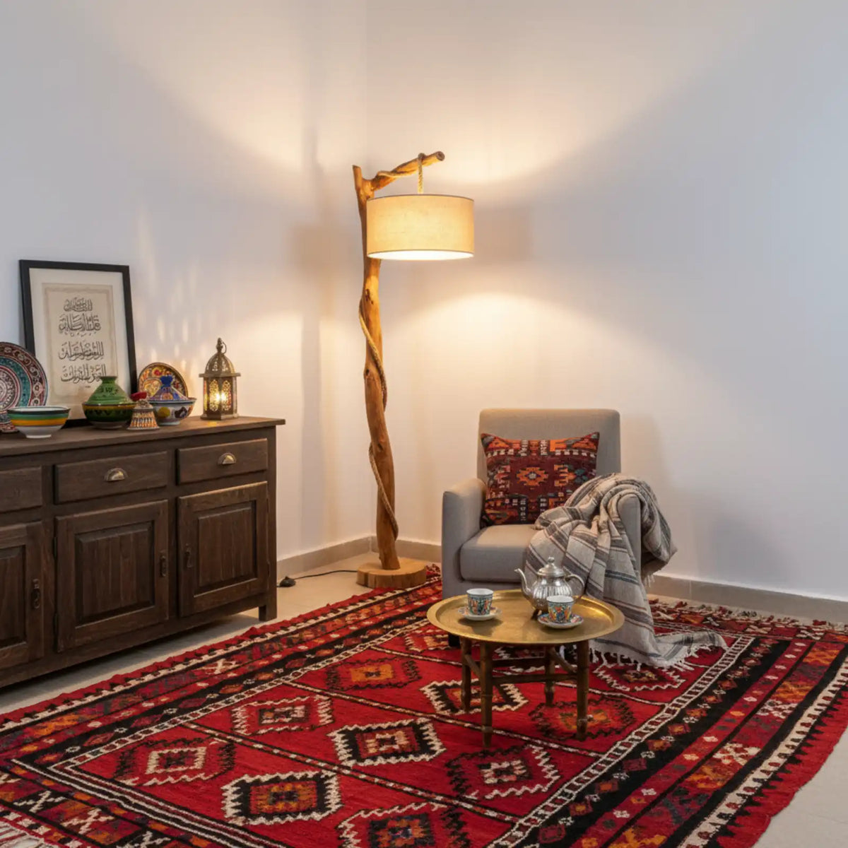 Lampe sur pied en bois flotté dans un salon oriental, avec tapis rouge à motifs, buffet en bois sombre et table plateau dorée