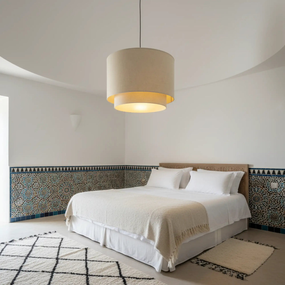 Suspension en lin beige allumée dans une chambre blanche avec frise en zellige et tapis berbère