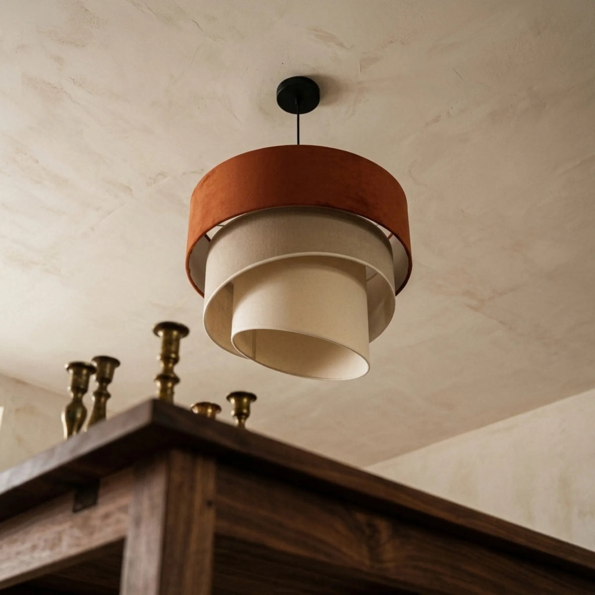 Vue de dessous du lustre en velours terracotta, spirales beige crème et bougeoirs en laiton