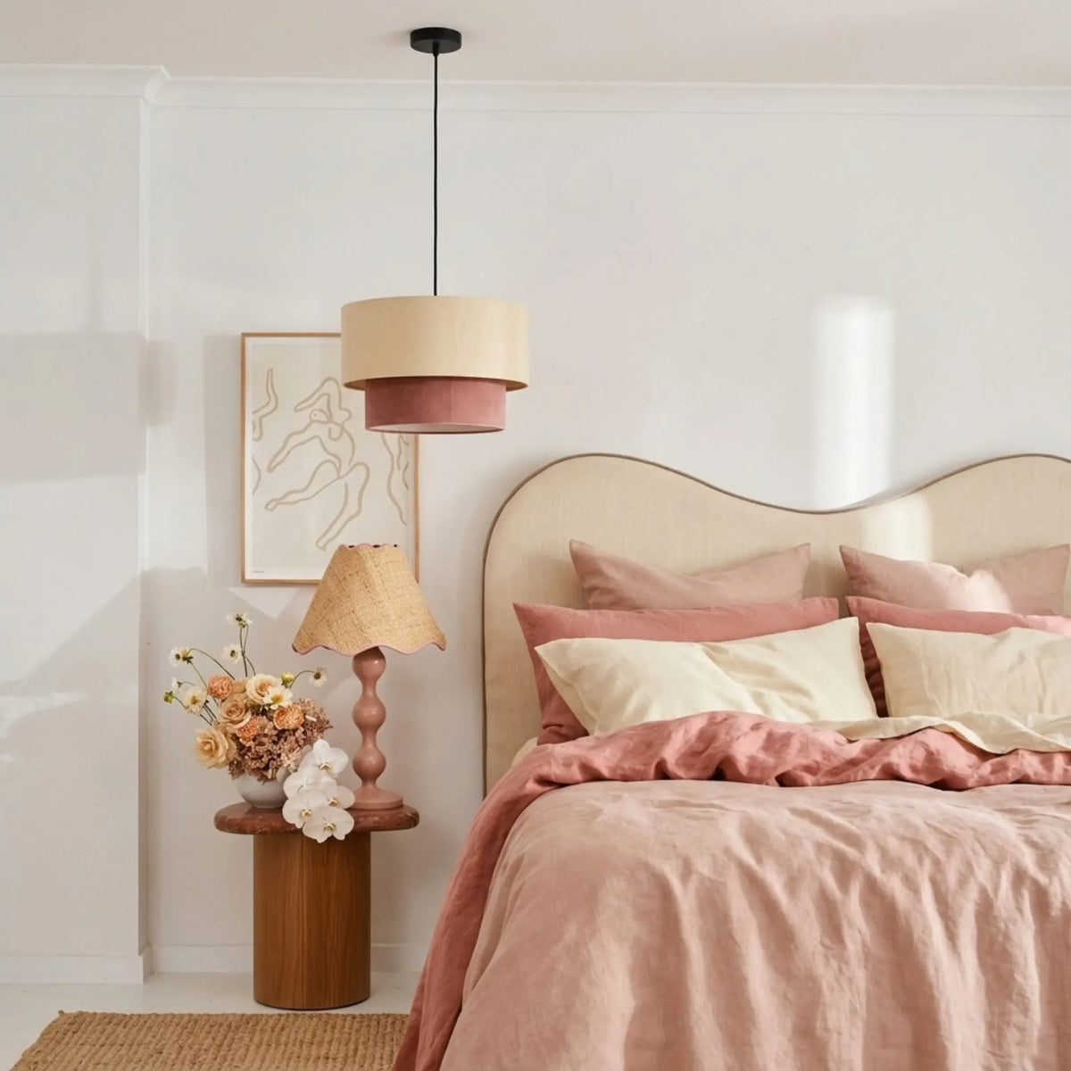 Suspension beige et vieux rose dans une chambre au linge de lit rose et tête de lit ondulée écrue