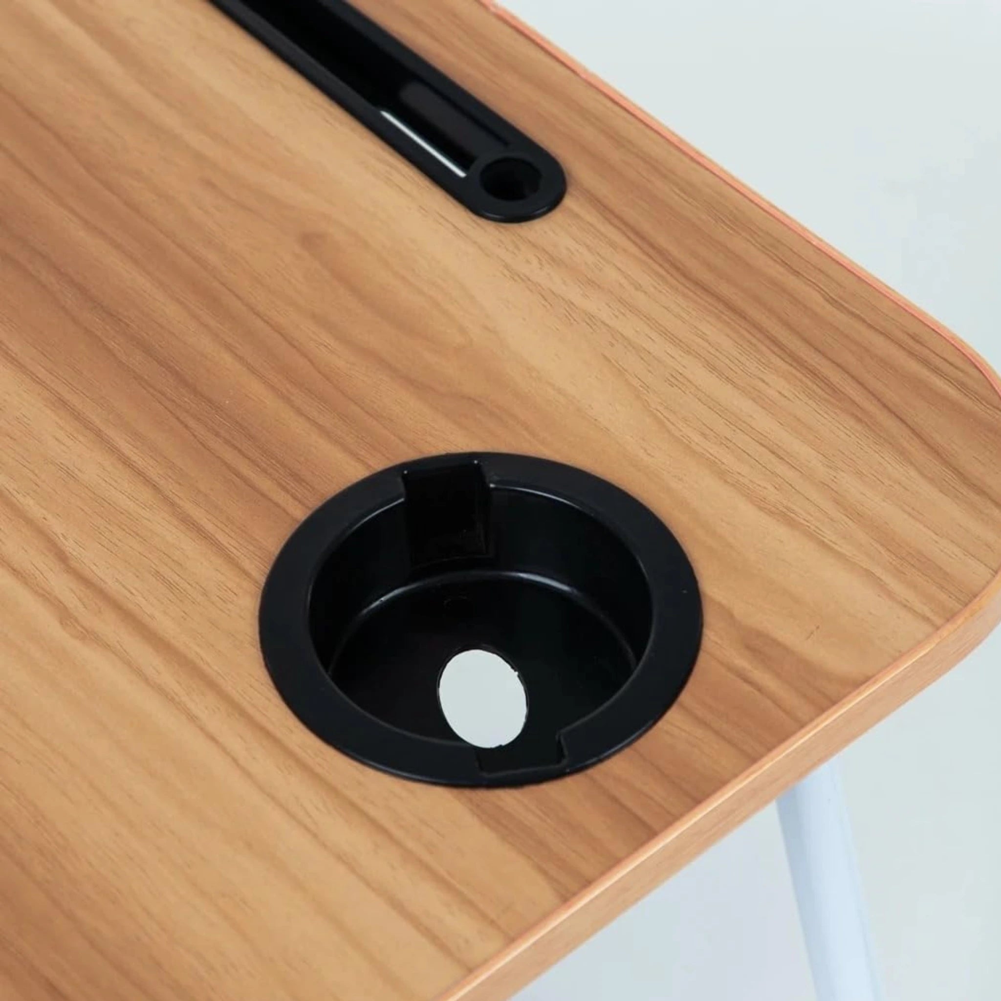 Détail du porte-gobelet intégré sur une table de lit pliante en bois clair, disponible en Tunisie.