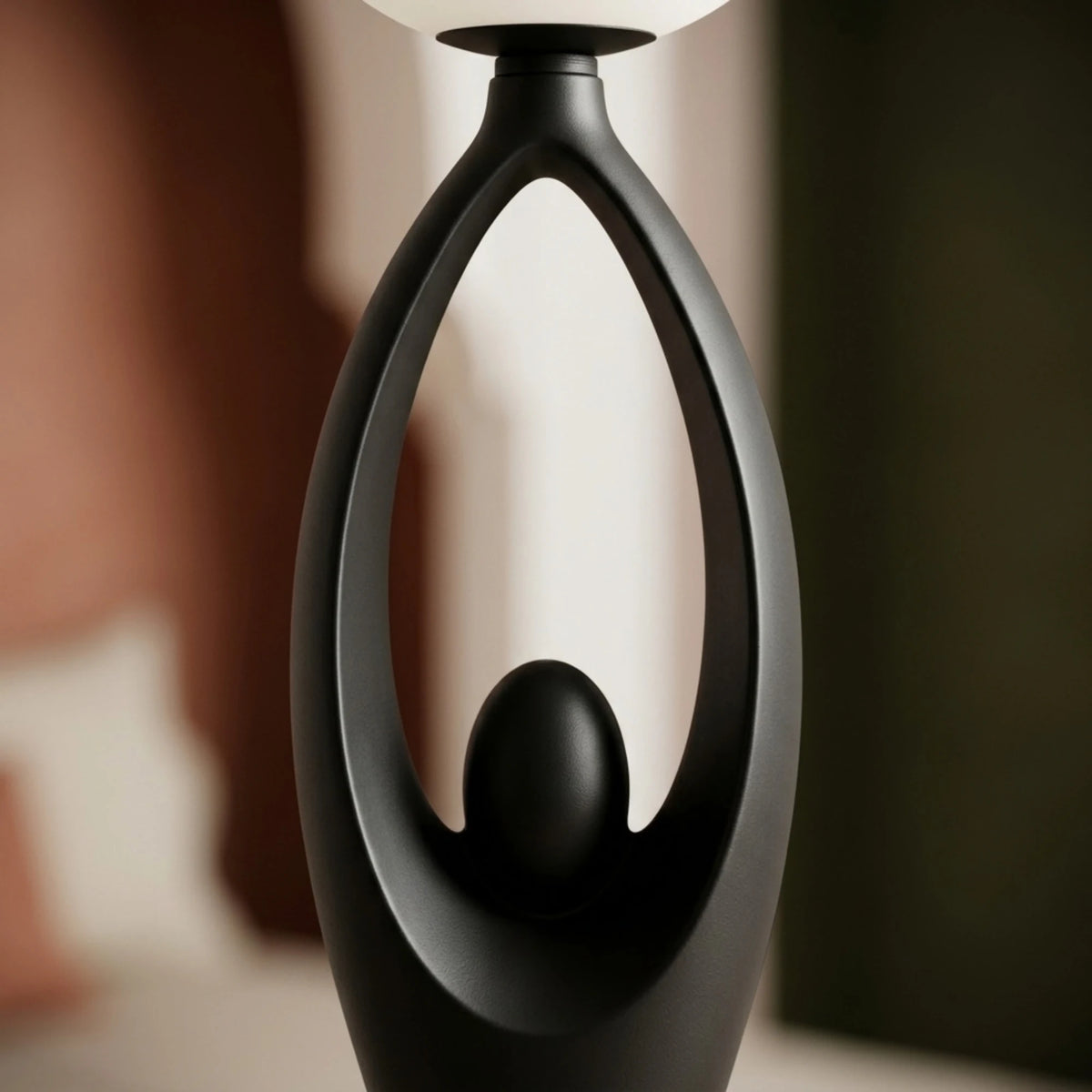 Gros plan sur la silhouette aux bras levés du lampadaire sculptural noir mat