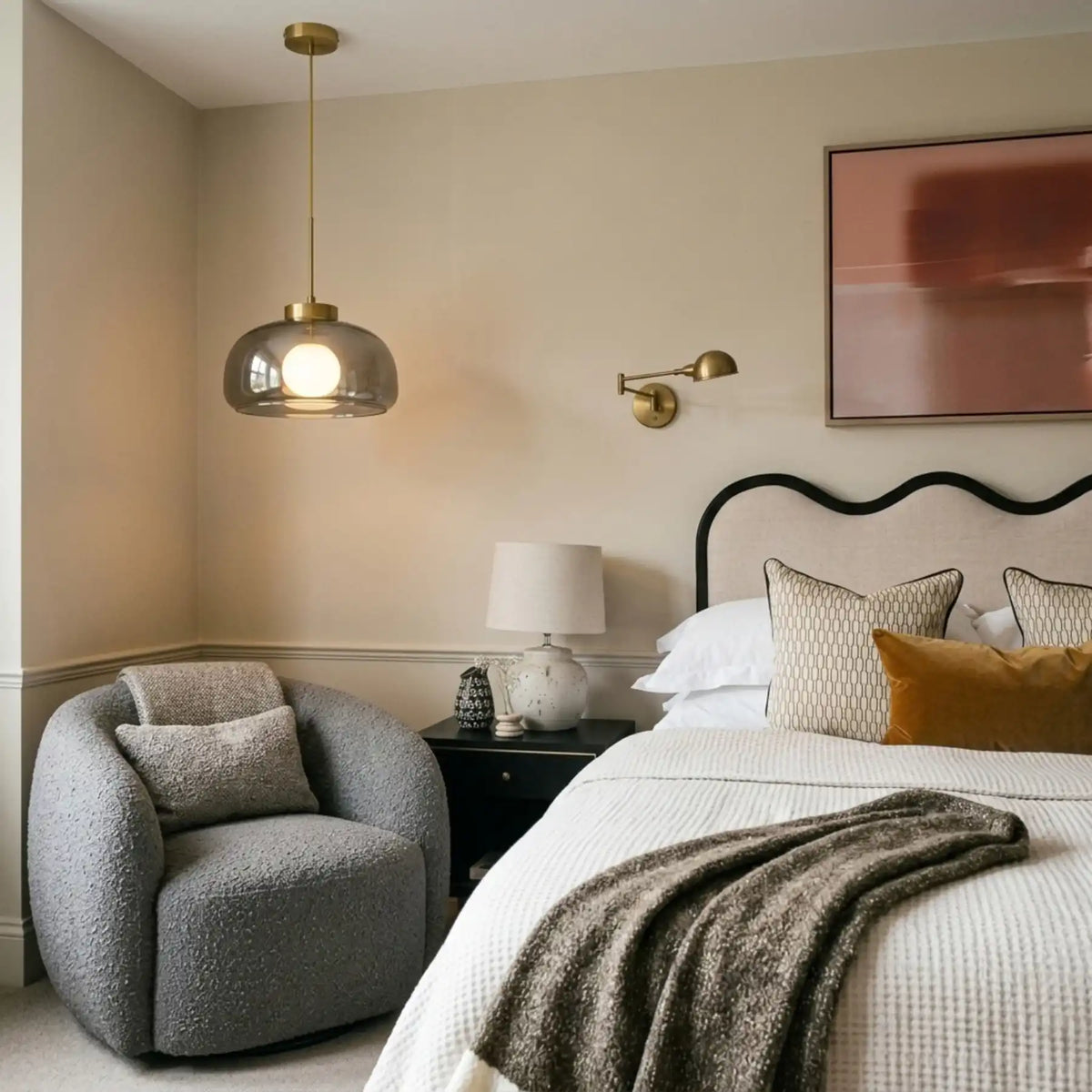 Lustre en verre fumé noir allumé dans une chambre, fauteuil bouclette gris et tête de lit ondulée