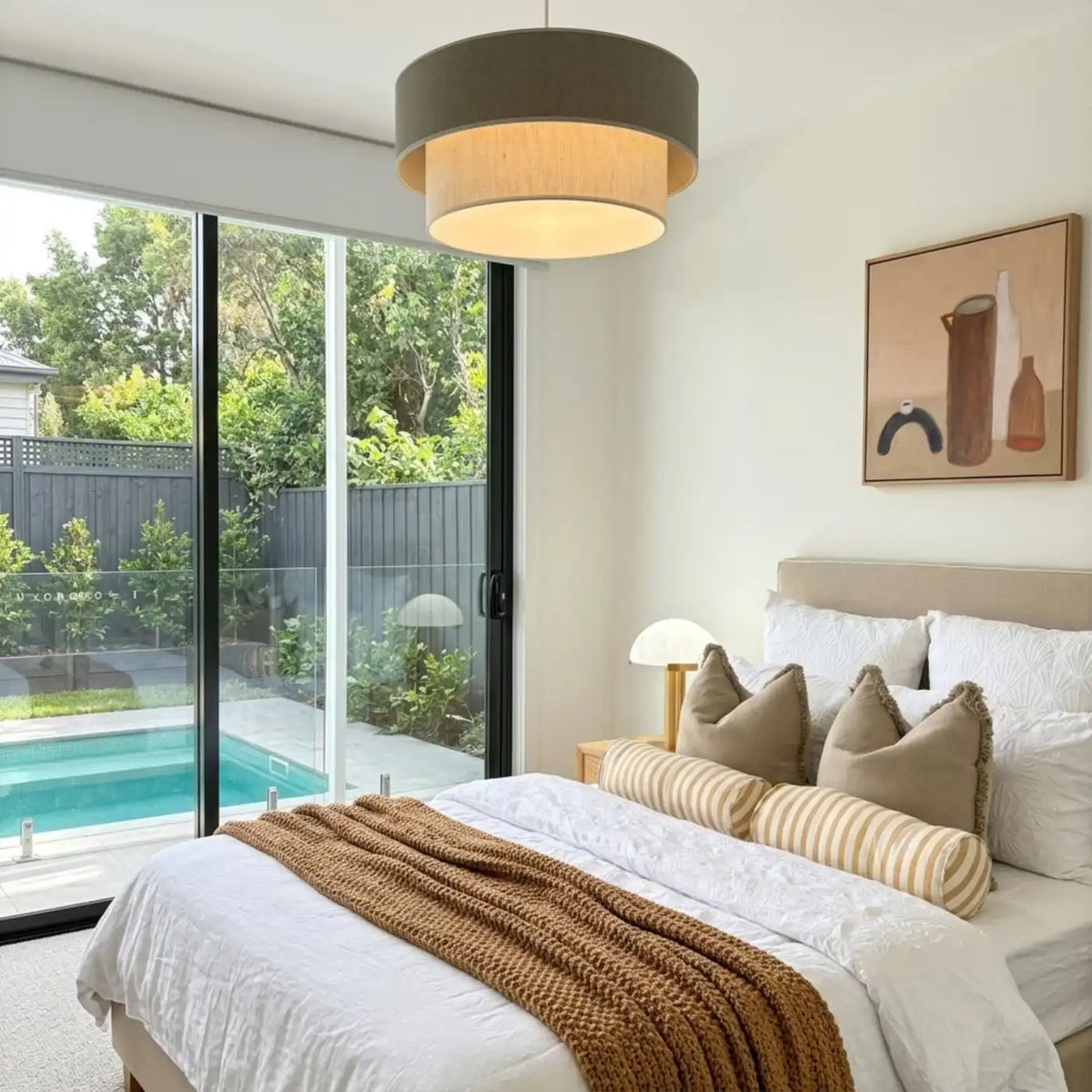 Suspension gris taupe et beige dans une chambre à baie vitrée ouverte sur une piscine