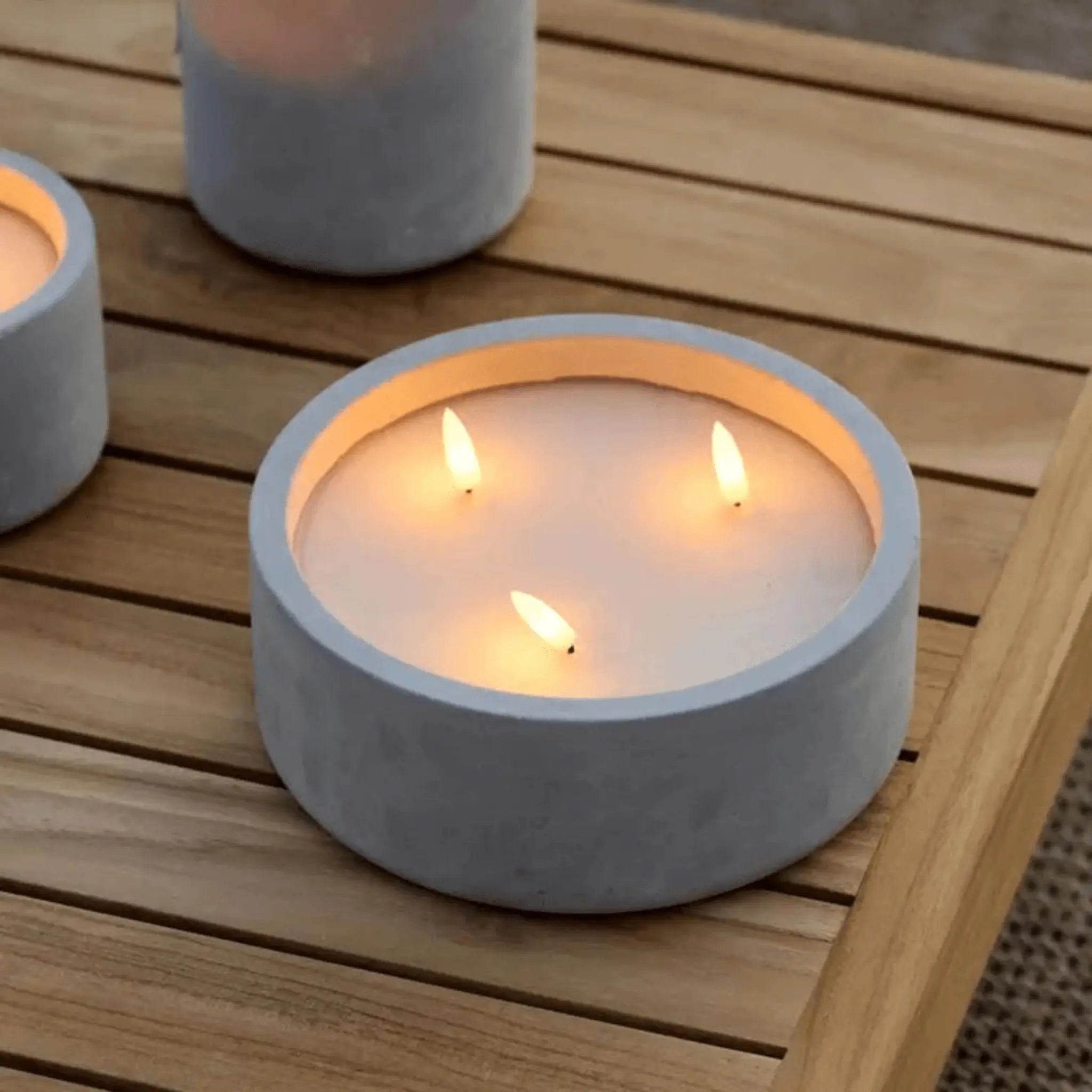 Bougie LED en béton, allumée sur une table en bois, créant une atmosphère cosy.