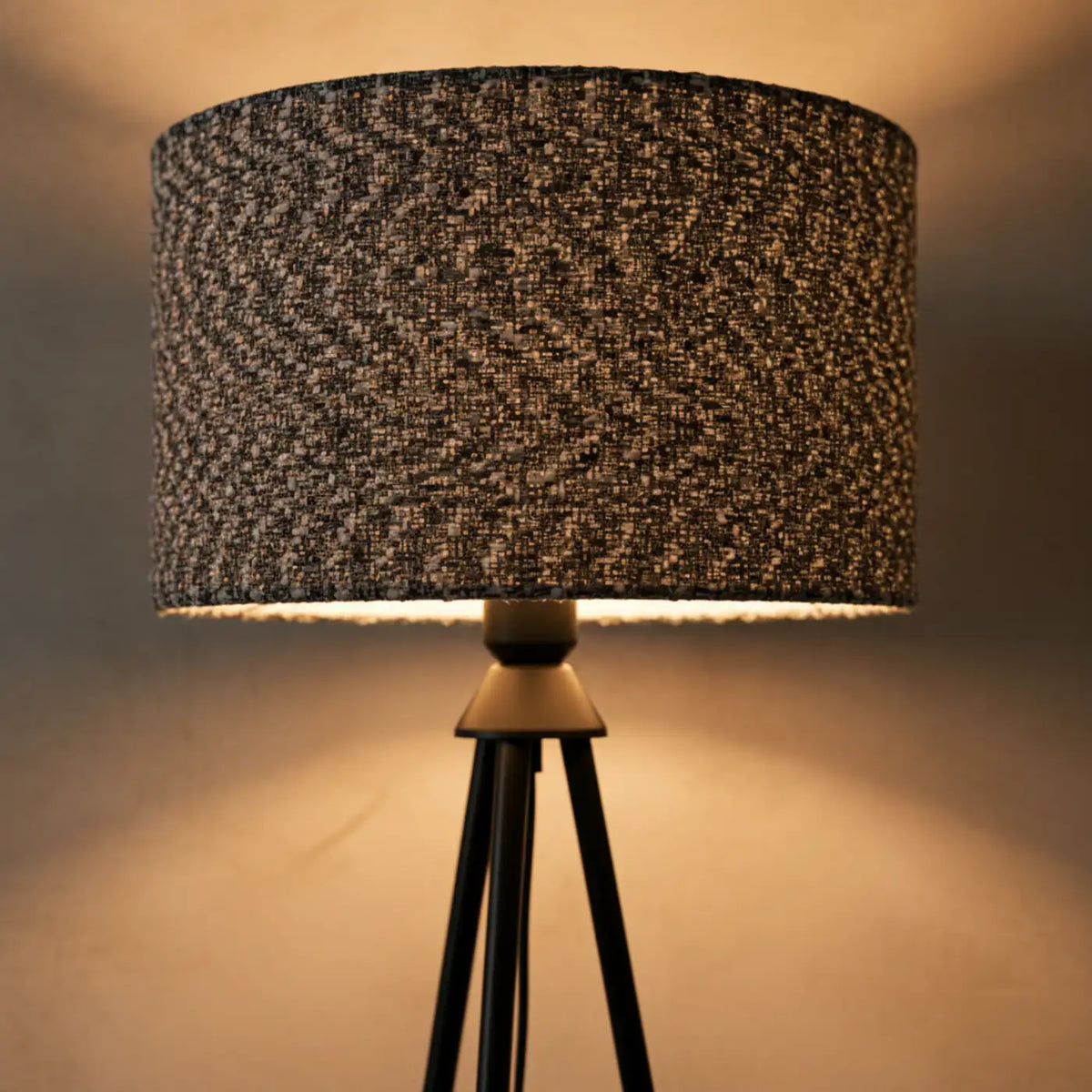 Abat-jour en tissu chiné allumé, lumière chaude filtrée par le tissage et diffusée vers le bas