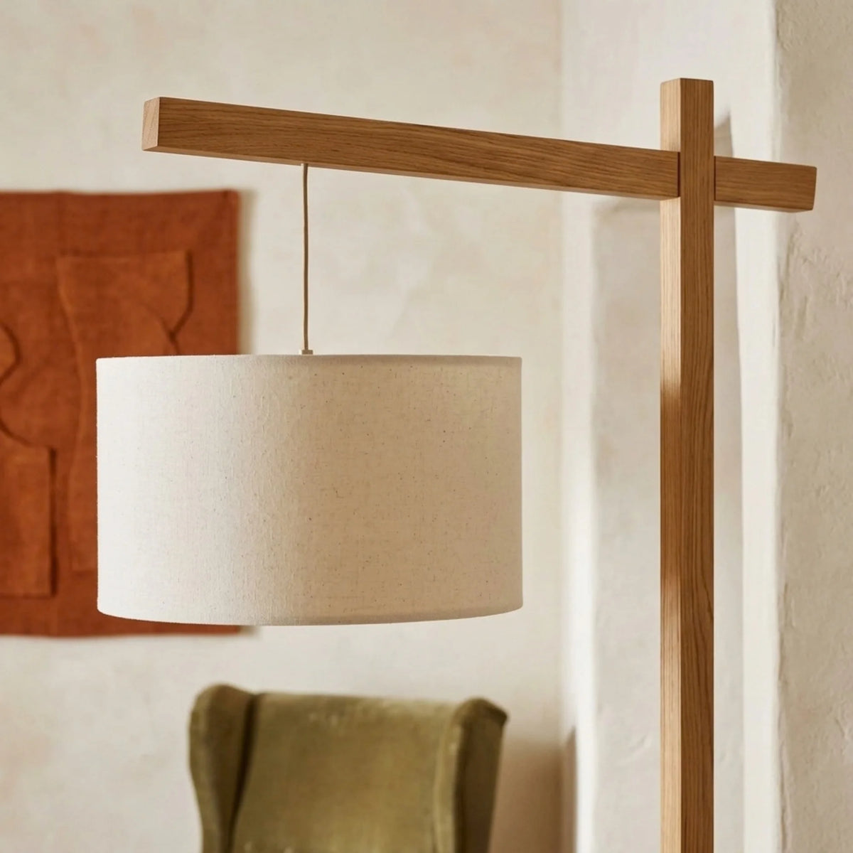 Gros plan de l'abat-jour tambour en tissu crème suspendu au bras en bois du lampadaire