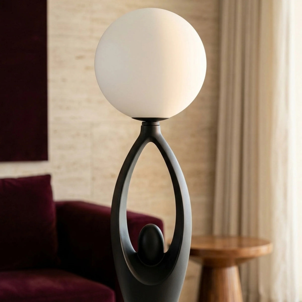 Globe en verre opalin blanc du lampadaire design noir près d'un fauteuil en velours bordeaux