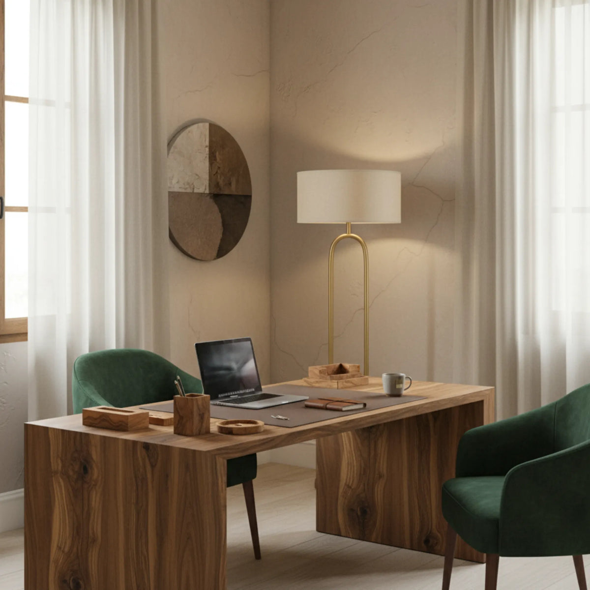 Lampadaire arceau doré dans un coin bureau, derrière une table en bois avec ordinateur portable et fauteuils verts