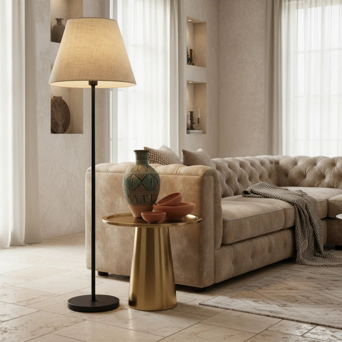 Lampadaire à abat-jour beige à côté d'un canapé capitonné beige et d'une table d'appoint dorée avec vase