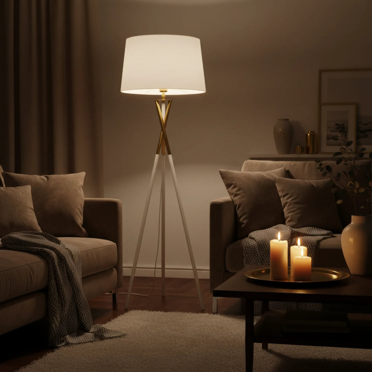 Lampadaire blanc et doré allumé dans un salon cosy, près d'un canapé brun et de bougies sur la table basse
