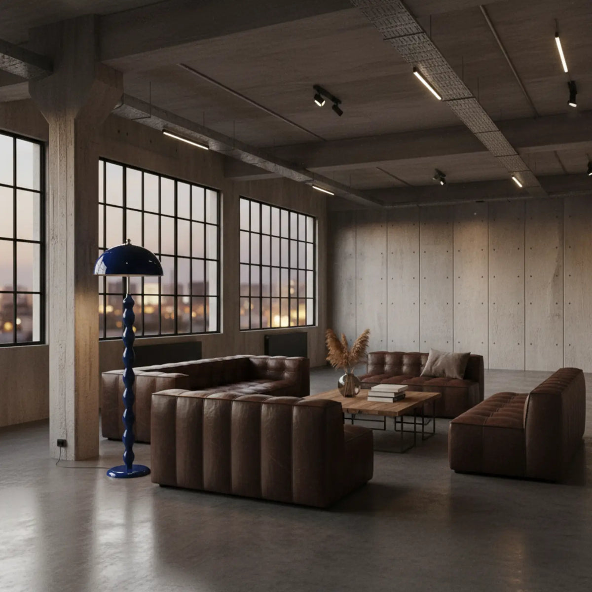 Lampadaire bleu dans un loft industriel avec canapés en cuir marron et grandes fenêtres