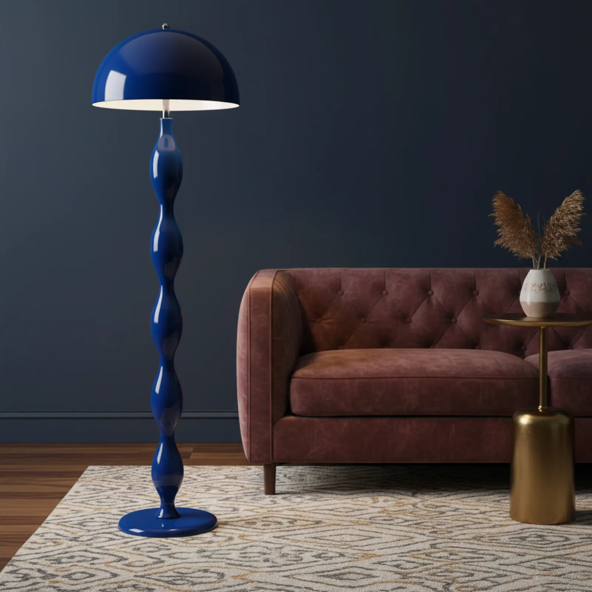 Lampadaire bleu devant un mur bleu nuit, près d'un canapé capitonné et d'une table d'appoint dorée