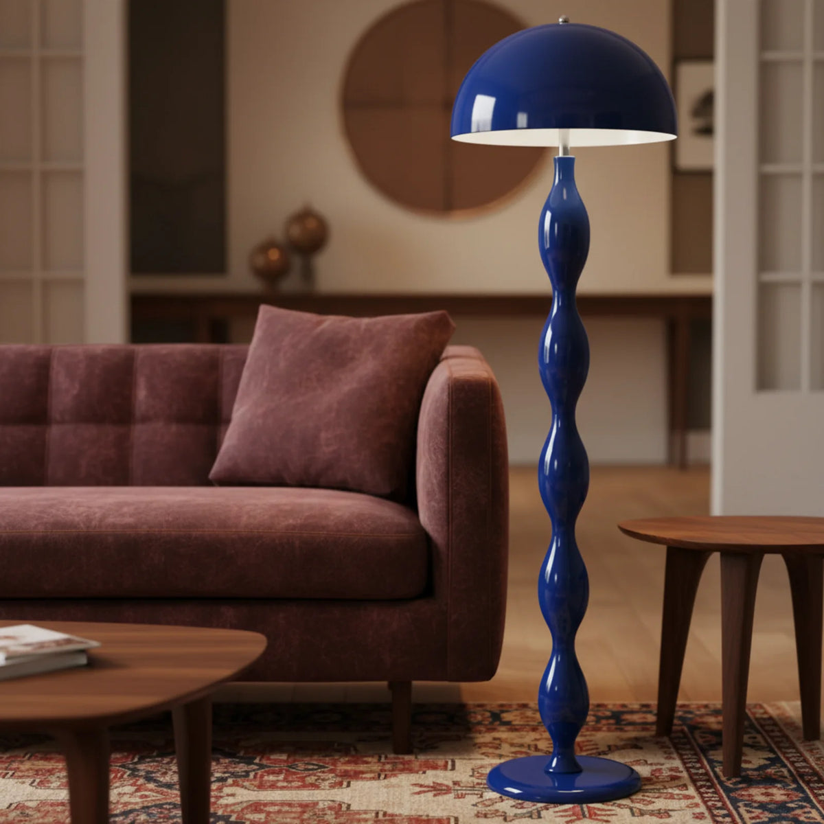 Lampadaire bleu à côté d'un canapé en velours bordeaux, sur un tapis oriental, avec tables en bois