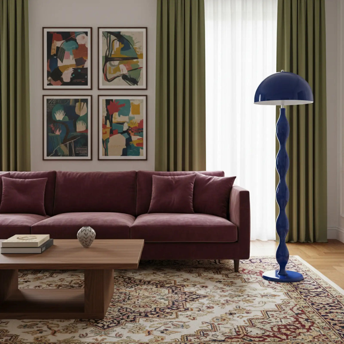 Lampadaire bleu à côté d'un canapé en velours prune, devant des rideaux vert olive et des tableaux abstraits