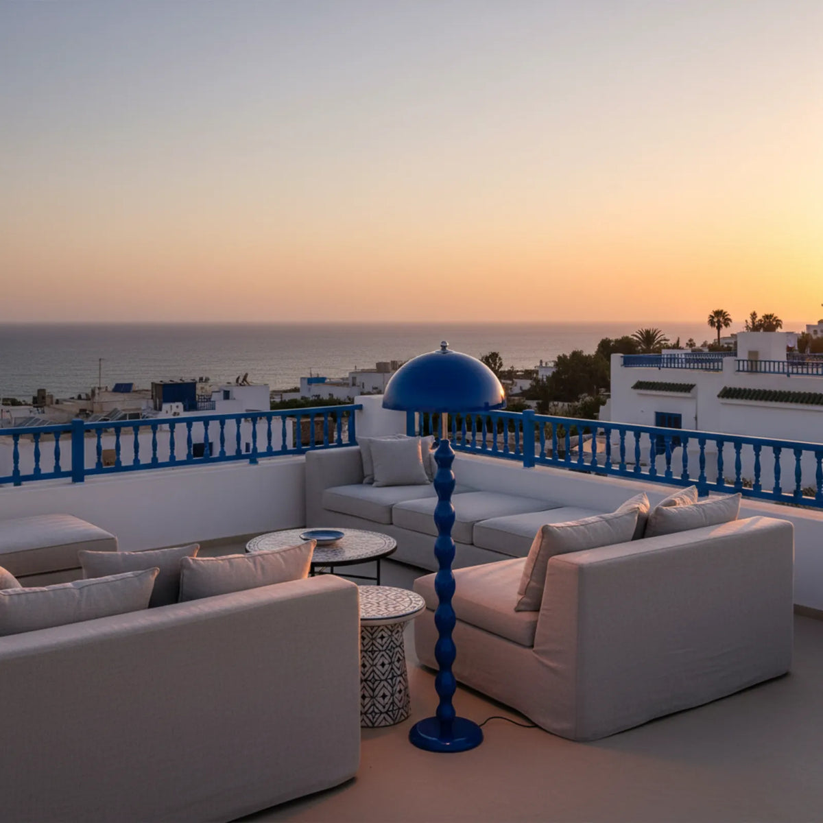 Lampadaire bleu sur un toit-terrasse blanc et bleu de style tunisien, au coucher du soleil face à la mer