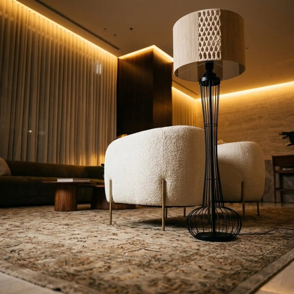 Lampadaire bohème chic en macramé à côté d'un fauteuil bouclette blanc, sur un tapis moelleux dans un salon tamisé