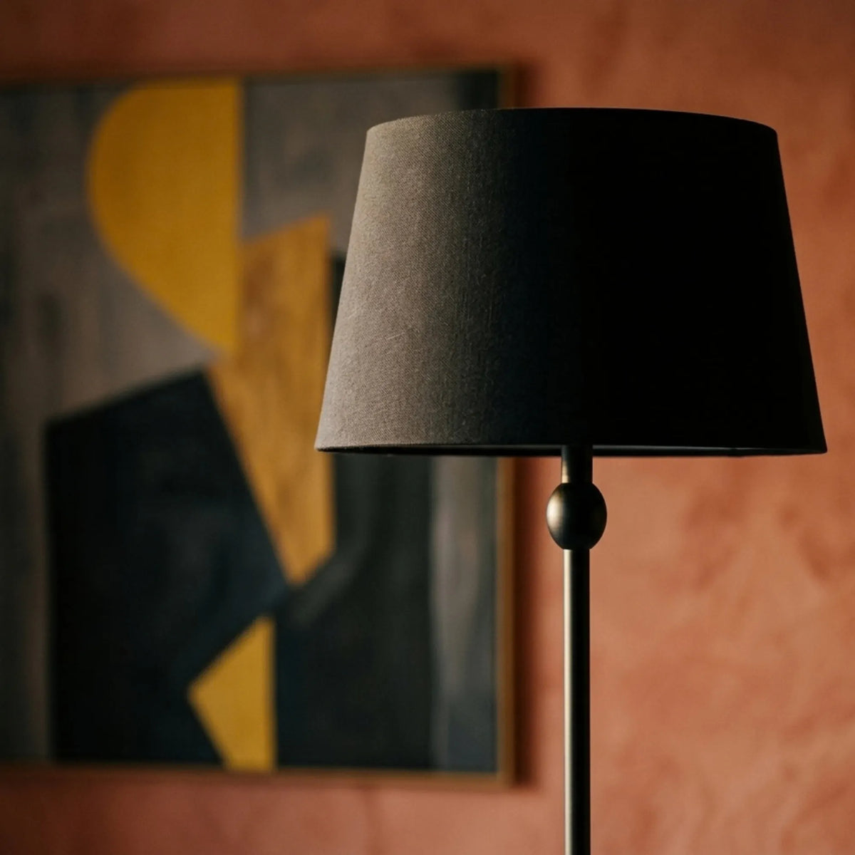 Détail de l'abat-jour noir et de la boule décorative du lampadaire classique, devant un mur terracotta