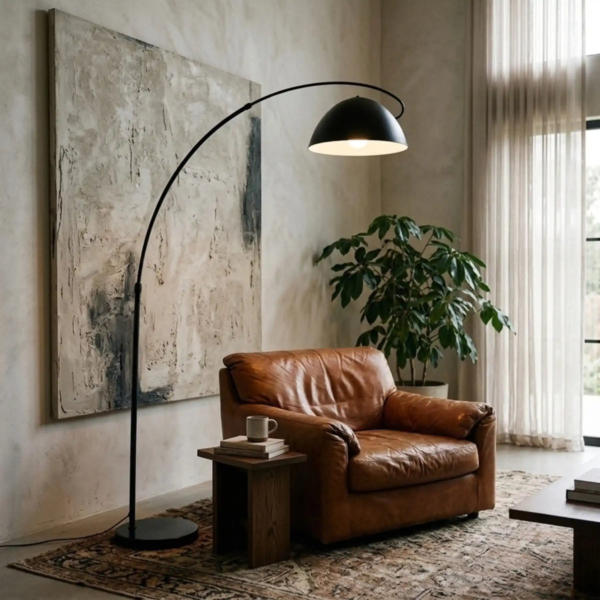 Lampadaire de lecture arc noir allumé au-dessus d'un fauteuil en cuir cognac et d'une table d'appoint en bois