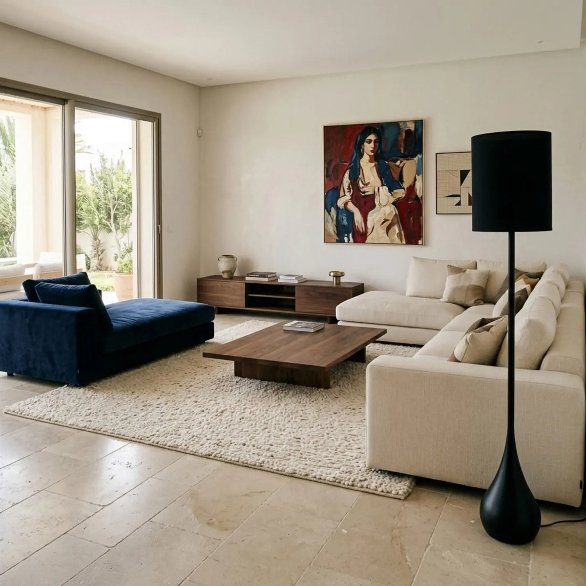 Lampadaire noir au premier plan d'un grand salon lumineux avec canapés crème et bleu marine