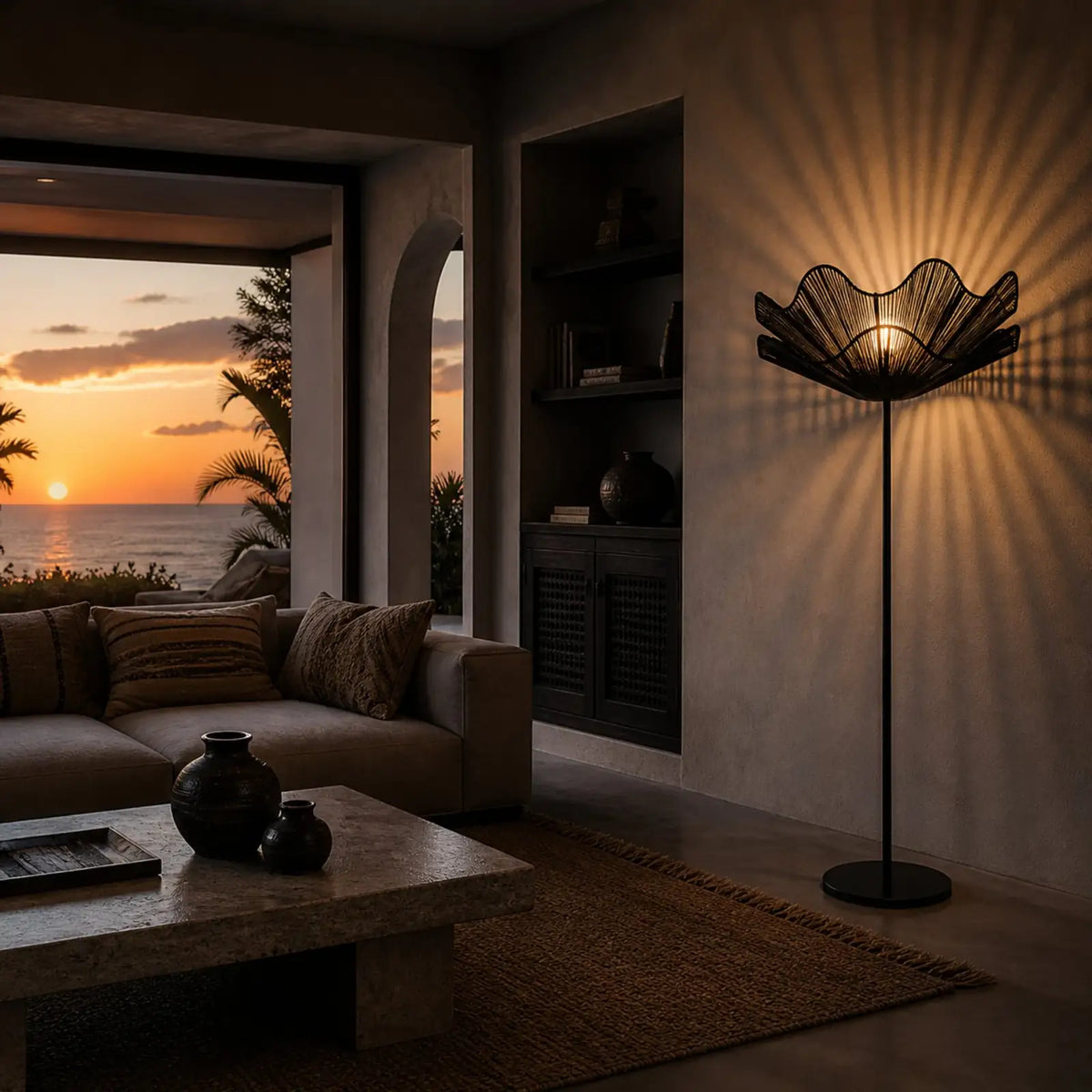 Lampadaire fleur noir projetant des rayons de lumière sur le mur d'un salon avec canapé et vue mer