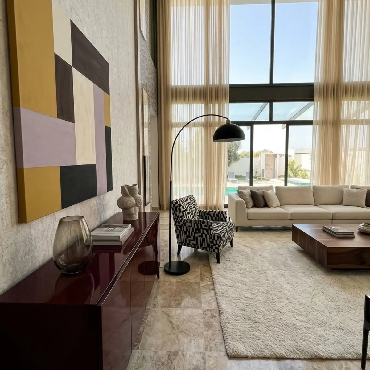 Lampadaire à dôme noir près d'un fauteuil à motifs graphiques noir et blanc et d'un tableau géométrique jaune et mauve