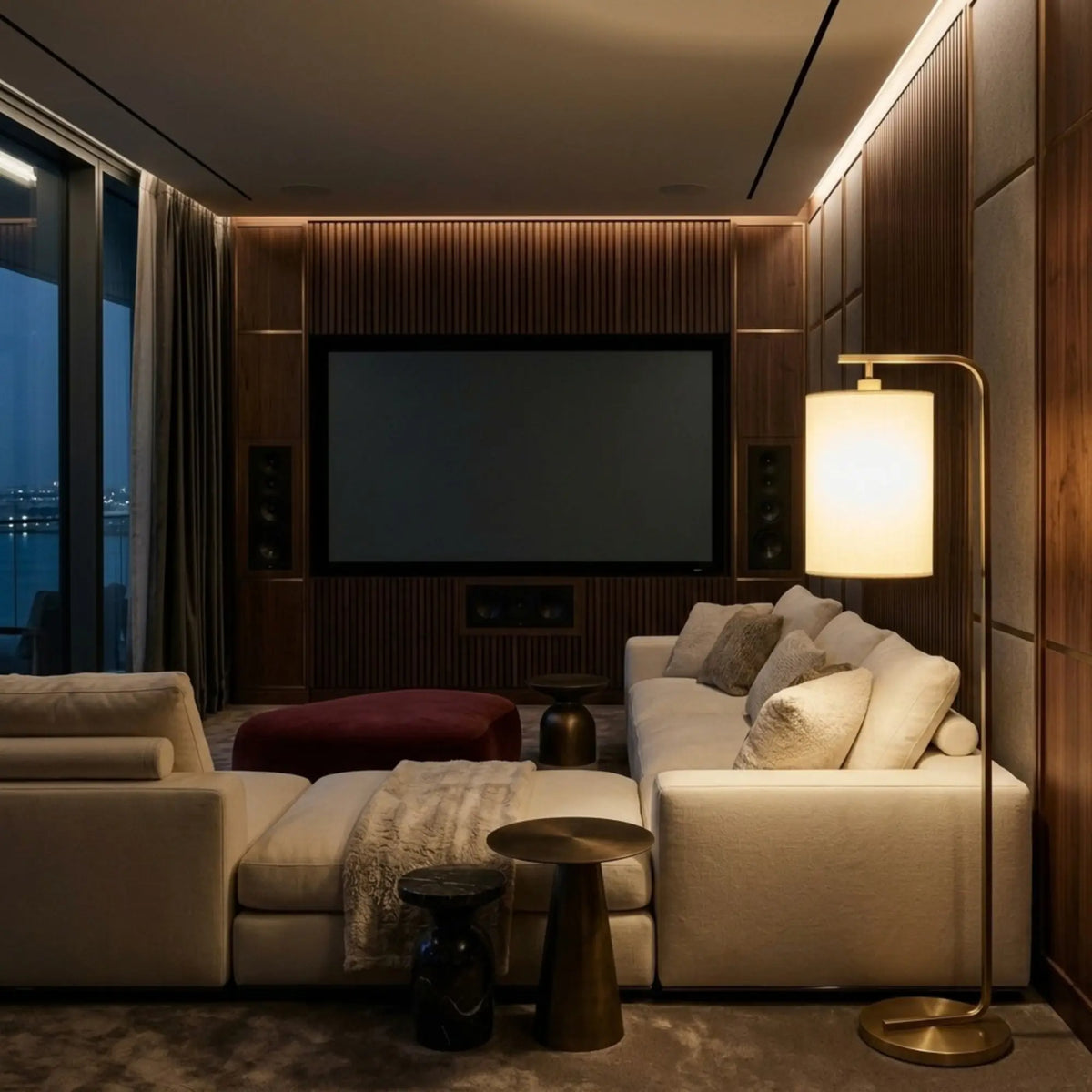 Lampadaire doré allumé dans une salle cinéma privée avec canapé modulable et écran mural